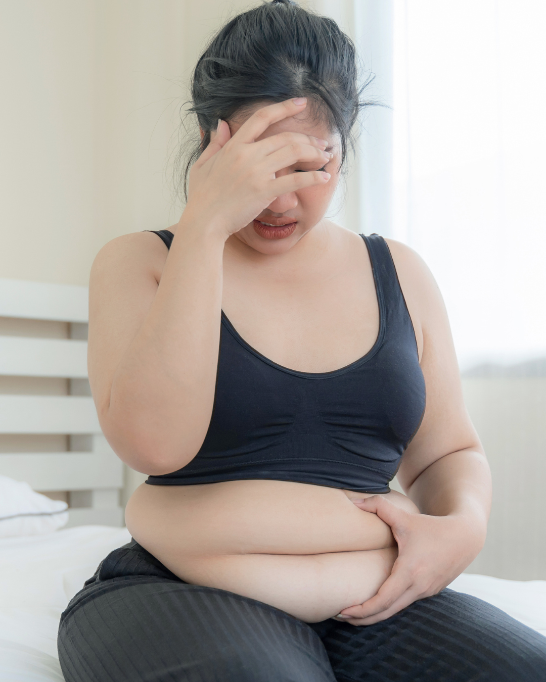femme assise tenant son ventre gonflé 