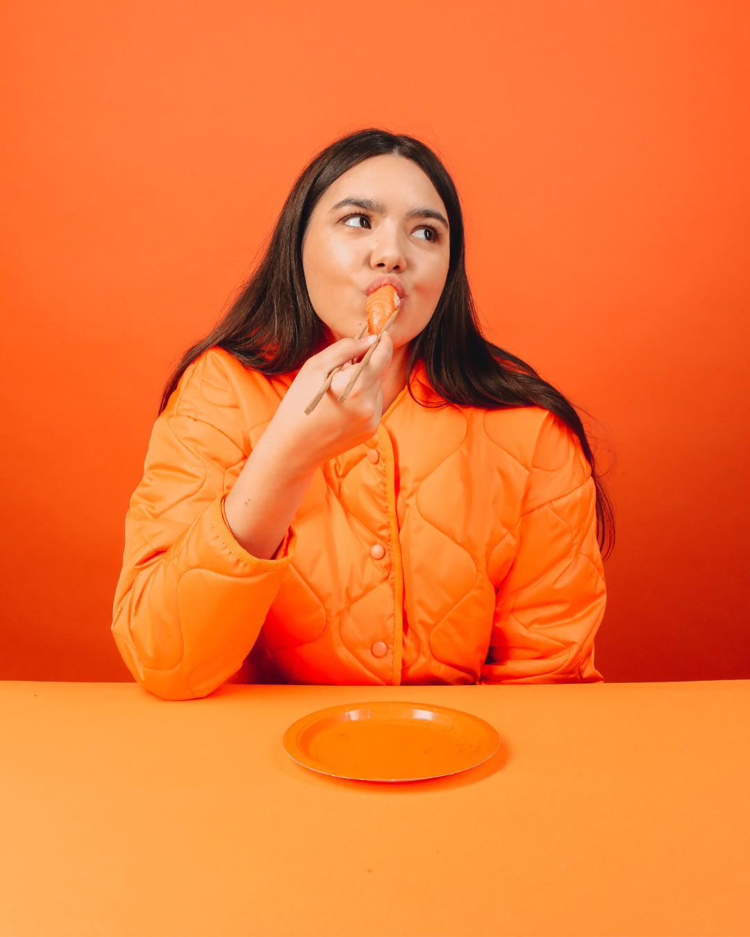 femme sur donf orange qui mange un sushi